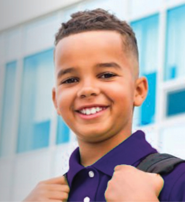 A smiling young boy with his backpack