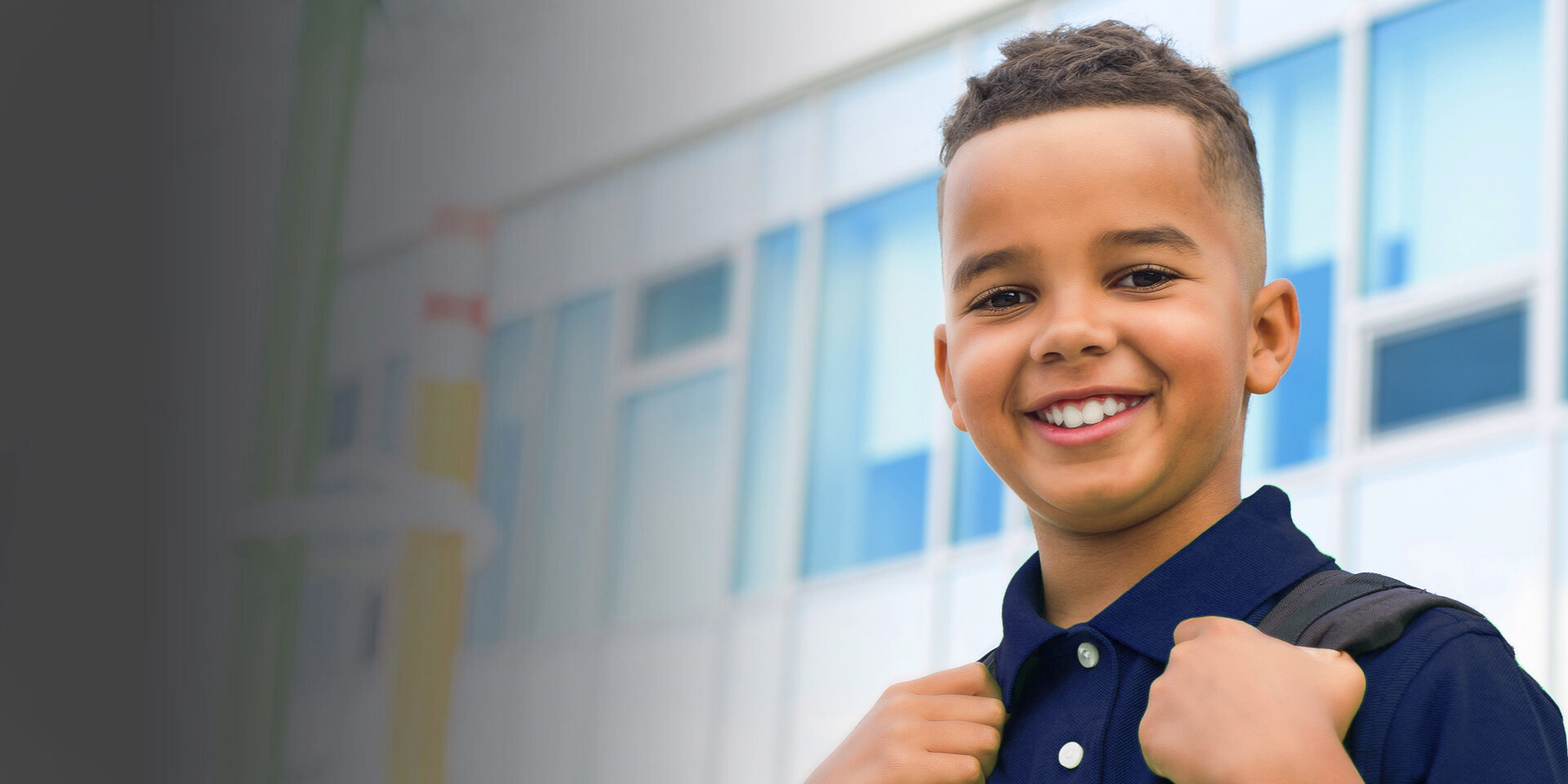 A smiling young boy with his backpack